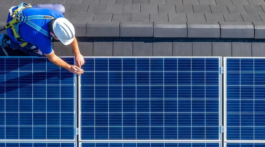 Worker installing photovoltaic panels on the roof
